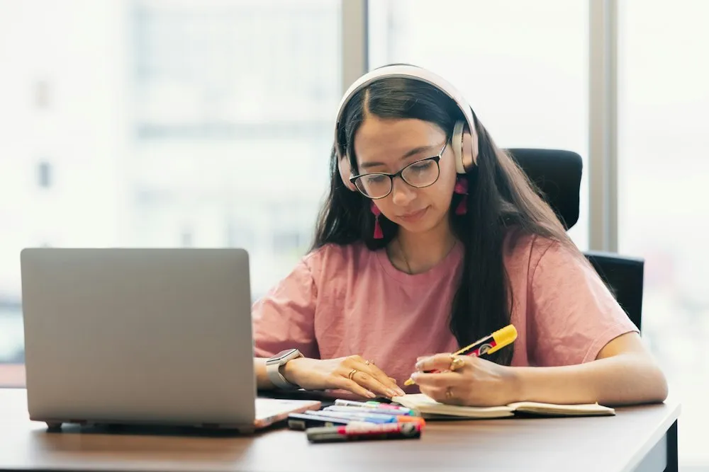 Young woman wearing headphones studying at a desk