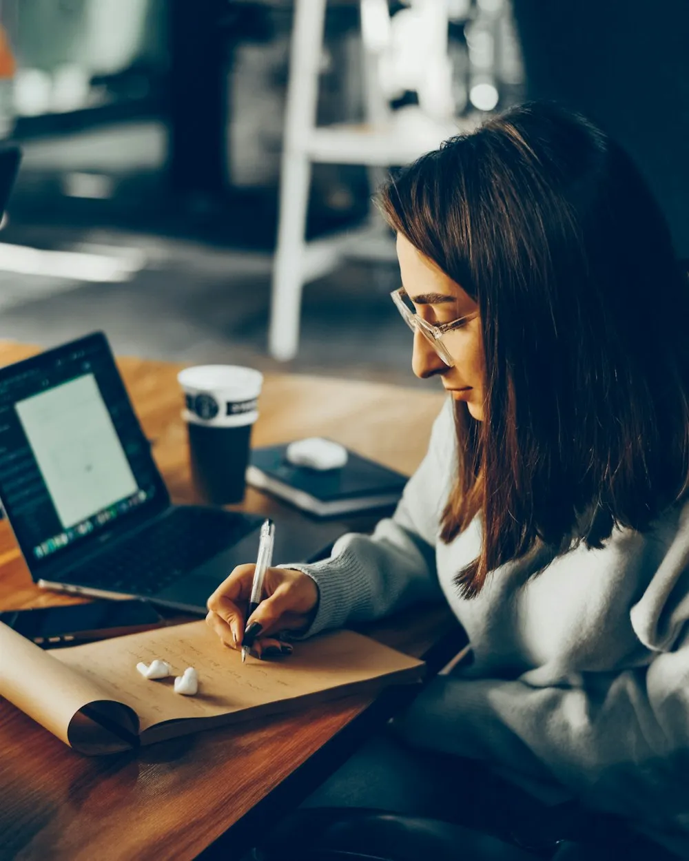 Woman studying and writing notes beside a laptop
