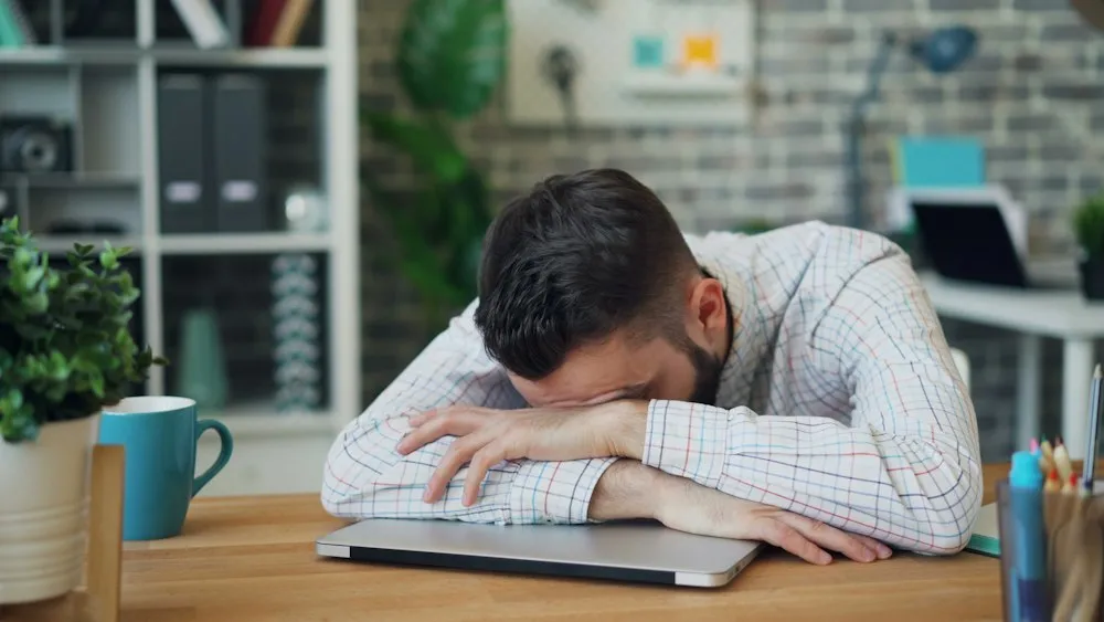 Tired man resting his head on his arms at his desk