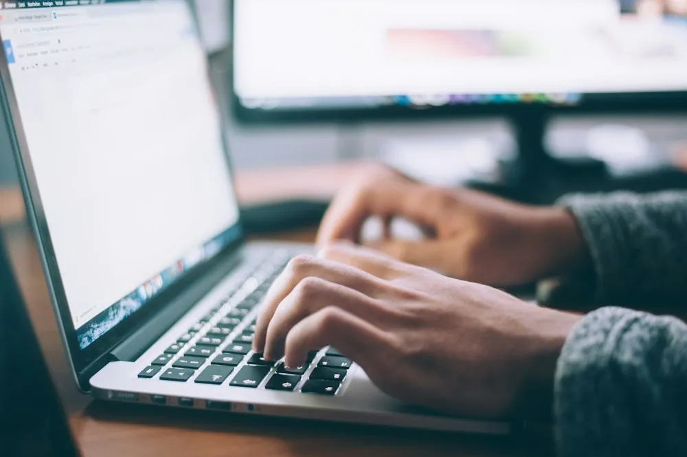 Person typing correspondence on a laptop