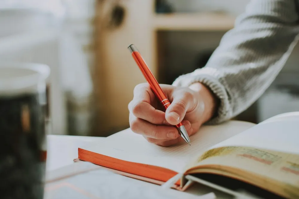 Student drafting an essay with a red pen